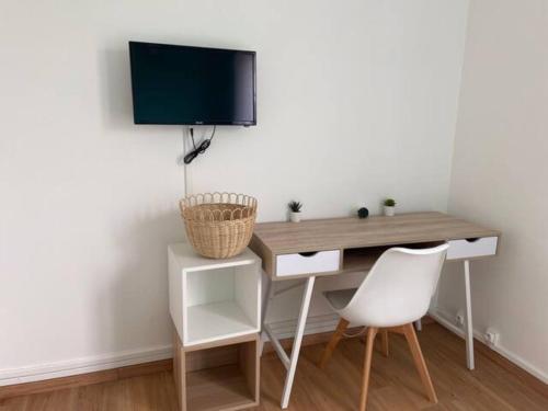蒙圣埃尼昂Chambre dans appartement lumineux的一张带白色椅子的桌子和墙上的电视