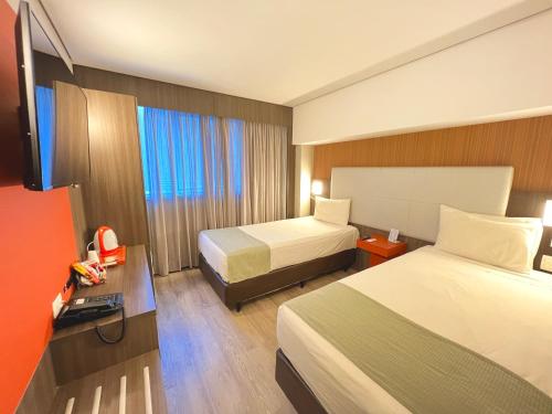 里约热内卢eSuites Hotel Recreio Shopping的酒店客房设有两张床和电视。
