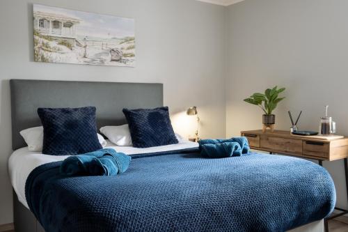 大雅茅斯Exclusive House with Canadian Hot Tub的一间卧室配有一张带蓝色毯子和枕头的床。