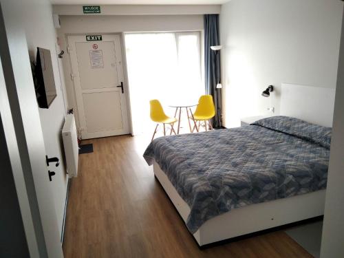 BogucinMotel Express的一间卧室配有一张床和两张黄色椅子