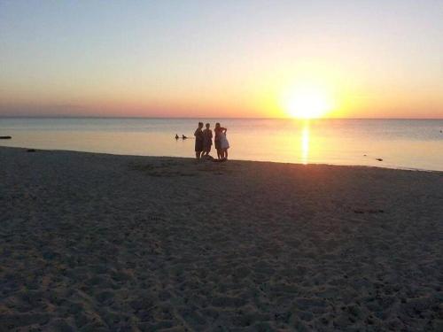 MellitaCoeur des iles的日落时分在海滩上散步的三人