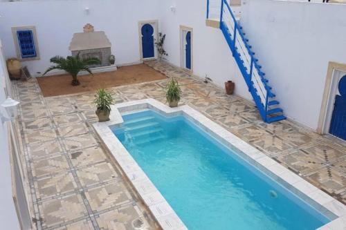 MellitaCoeur des iles的一座位于房子中间的游泳池,铺有瓷砖地板