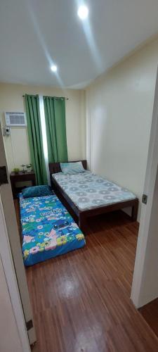 DapitanAffordable Home stay with 3 bedroom near CCLEX的绿窗帘间内的两张床