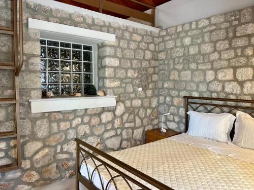 DidymaCasa Matina, GcollectionGr的一间卧室设有石墙、一张床和一个窗口