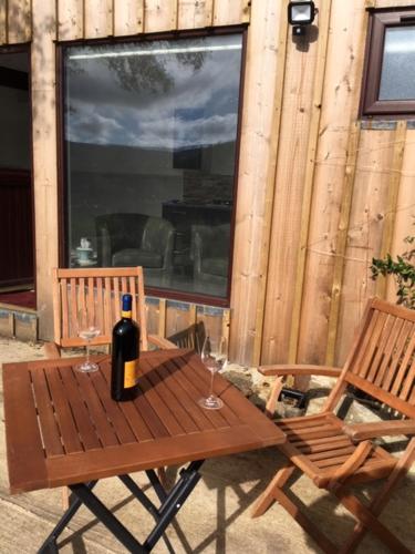 LettermacawardAde's River Cabin的一张木桌、一瓶葡萄酒和两把椅子