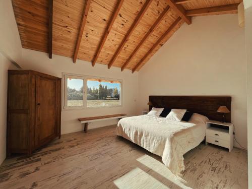 圣卡洛斯-德巴里洛切Casa de Campo La Chacra的一间卧室设有一张床和木制天花板