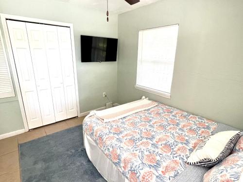 可可比奇Beach Bungalow in downtown Cocoa Beach的一间卧室设有一张床、一台电视和两个窗户。