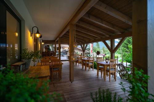 皮勒尔湖畔圣乌尔里希Hotel Landhaus Tirolerherz的一间在甲板上配有木桌和椅子的餐厅