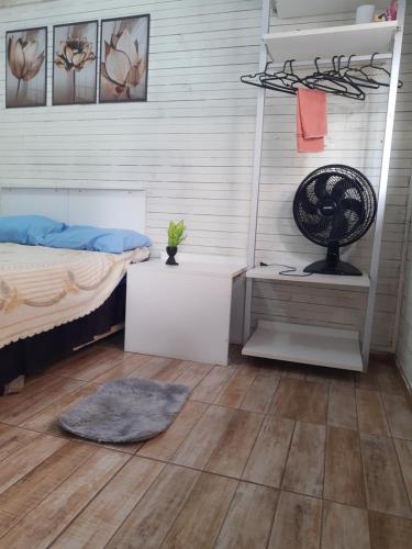 弗洛里亚诺波利斯TownhouseFloripa II Praia do Moçambique-RioVermelho的一间卧室配有一张床和一张带风扇的书桌
