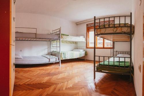 奥赫里德Sunset Lake hostel的客房设有三张双层床,铺有木地板。