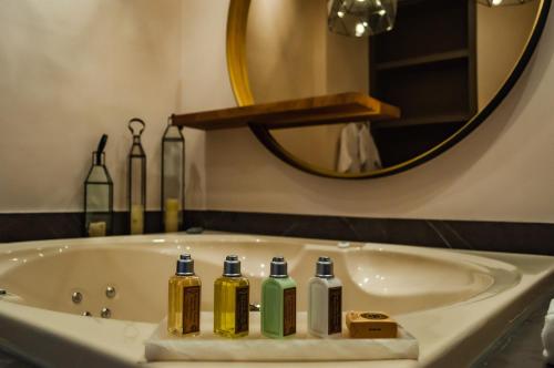 Los GalvanesCasa Raíces Hotel Luxury & Viñedo的浴室设有浴缸,内有4瓶