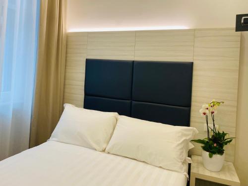 米兰Hotel Fioralba的一张带白色床单和蓝色床头板的床