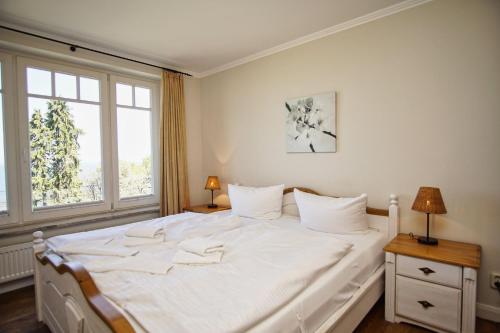 洛默Ferienwohnung mit traumhaftem Meerblick - Haus am Meer FeWo 07的卧室内的一张白色床,设有窗户