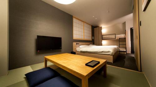 福冈ALPHABED INN Fukuoka Ohori Park的一间酒店客房,配有一张床铺、一张桌子、一张床和一台电视。