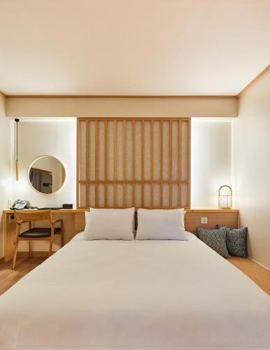 南海郡Tomonoya Signature Ryokan Namhae的卧室配有一张白色大床和一张书桌