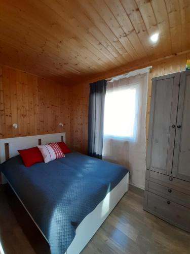 LubogoszczPrzyjazne domki的一间卧室配有一张蓝色的床和窗户