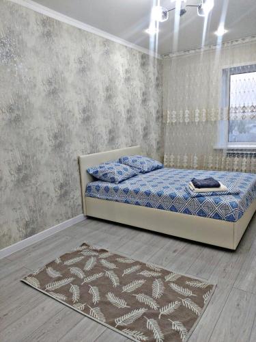 乌拉尔斯克Абая 244的一间卧室配有一张床和地毯