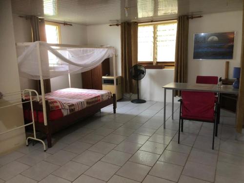 帕拉马里博Unu Pikin Guesthouse的一间卧室配有一张床、一张桌子和一张桌子