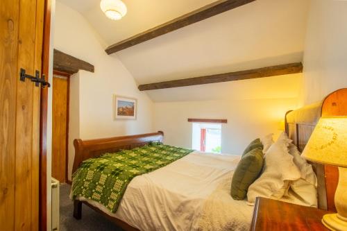 贝图瑟科伊德Maes Madog Cottages的一间卧室配有一张带绿毯的床
