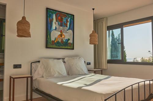 巴古尔L'Aixart Aiguablava Hotel的卧室配有一张床,墙上挂有绘画作品
