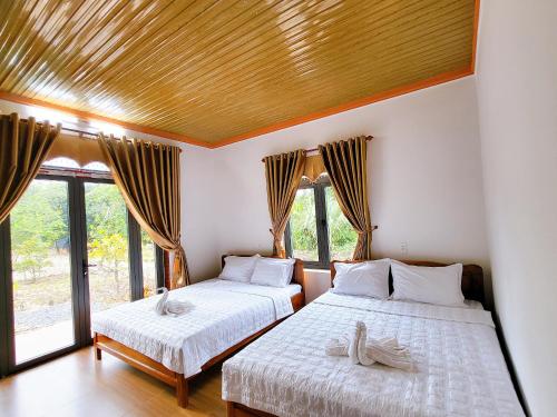 吉仙Thuy Tien Ecolodge的配有窗户和木制天花板的客房内的两张床