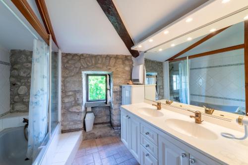吕奥姆La Médiévale - Charmante maison de caractère的浴室配有2个盥洗盆、浴缸和淋浴。