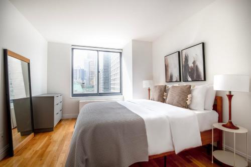 纽约1BR nr Broadway w Indoor pool Gym NYC-28的白色卧室设有一张大床和两个窗户