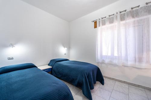 卡尔博尼亚B&B il Rifugio的卧室设有两张床,配有蓝色的床单和窗户。