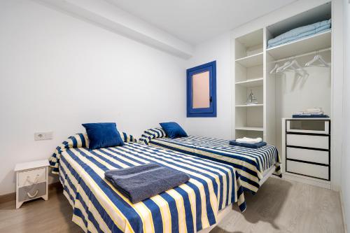 卡拉费尔La Casa del Pescador Calafellmar的一间卧室配有两张蓝色和白色条纹的床