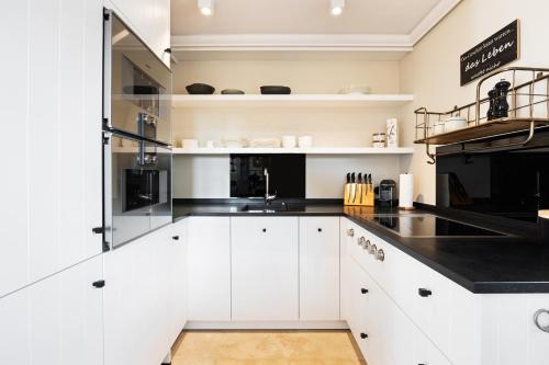 兰图姆Ferienhaus Miarwuefki的厨房配有白色橱柜和黑色台面