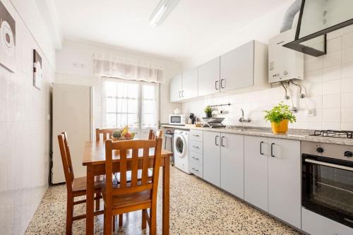 塞辛布拉Casa Alto da Serra Sesimbra的厨房配有白色橱柜和桌椅