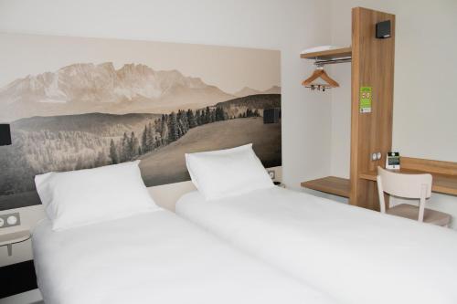 艾克斯河畔格雷西B&B HOTEL Aix-les-Bains的一间卧室设有两张床,墙上挂着一幅画