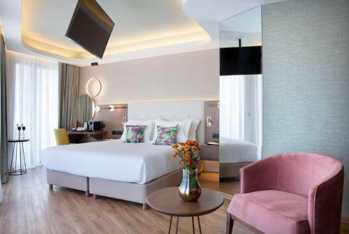雅典雅典温德姆公寓酒店的卧室配有白色的床和粉红色的椅子