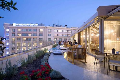 雅典雅典温德姆公寓酒店的一座带桌椅的屋顶露台和一座建筑
