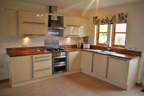 安斯特拉瑟Faolin- superb detached family villa East Neuk的厨房配有白色橱柜和炉灶烤箱。