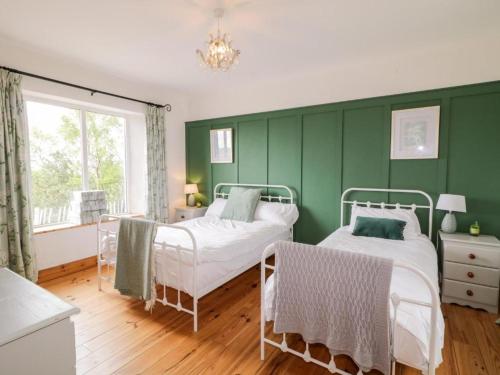 CarrigartLough View Cottage的绿色卧室设有两张床和窗户