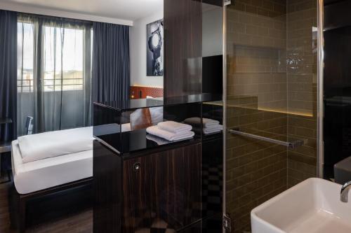 柏林Hotel MANI by AMANO的一间带玻璃淋浴和水槽的浴室