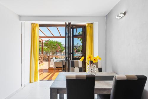 圣地亚哥港Neptuno Pool and beach private access的一间设有桌子和黄色窗帘的用餐室