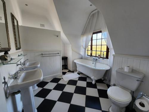 德班维尔黑巧克力旅馆的一间带两个盥洗盆、浴缸和卫生间的浴室