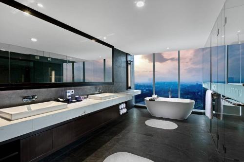 诗都阿佐ASTON Sidoarjo City Hotel & Conference Center的一间带两个盥洗盆、浴缸和窗户的浴室