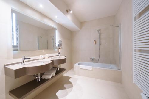 迪南莫里尼花园酒店的一间带水槽、浴缸和镜子的浴室