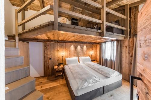 卡纳泽伊Rifugio Salei的一间卧室设有高架床和木墙