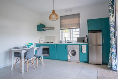 Coteau RaffinLe Rivage Appartement Mauritius的厨房配有绿色橱柜和桌椅