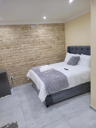 开普敦MIRAJO Guest House的一间卧室设有一张大床和砖墙