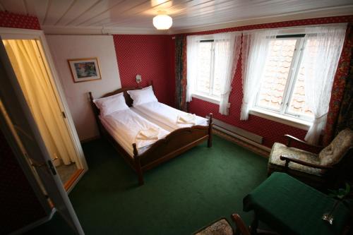 SkudeneshavnNorneshuset Overnatting的一间卧室配有一张床、一把椅子和窗户。