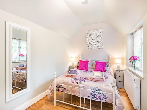 布利斯顿Pittendrigh Cottage的一间卧室配有一张带粉红色枕头和镜子的床