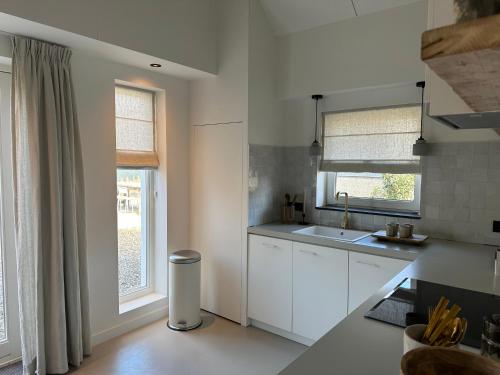 BeersStijlvol huisje in de Brabantse natuur! Tuynloodz B的厨房配有白色橱柜、水槽和窗户。