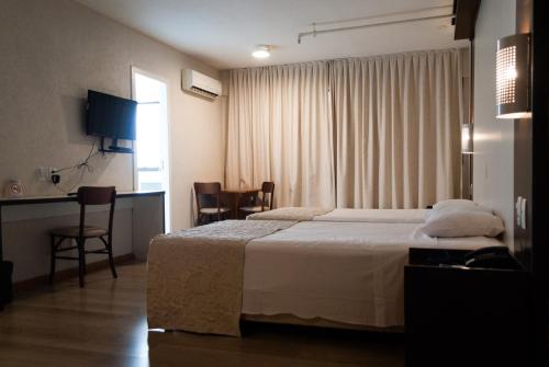 阿雷格里港Master Express Moinhos de Vento的酒店客房带一张床、一张桌子和椅子