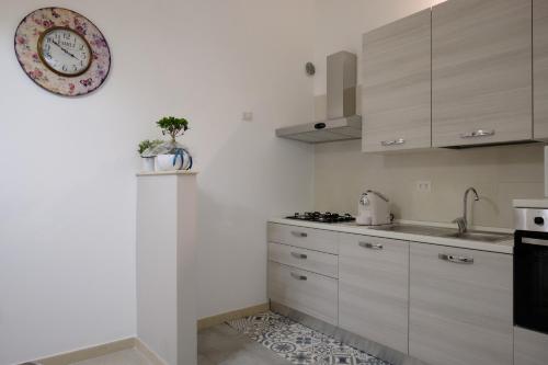 莫尔费塔Luma ospitalità的厨房配有白色橱柜和墙上的时钟