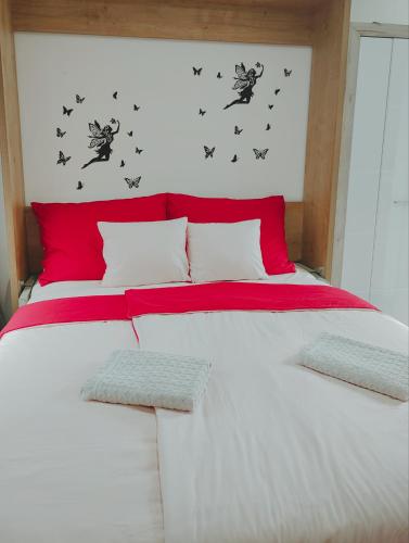 里耶卡Nika 2的一张铺有红白床单的床和墙上的蝴蝶